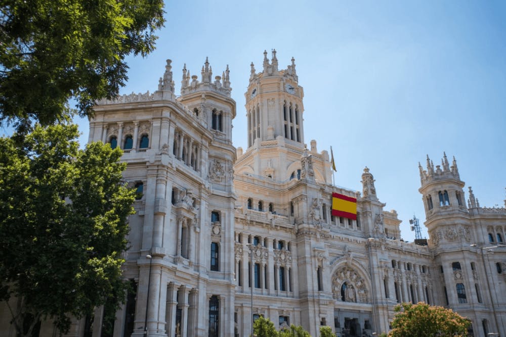 An ornate building with a spanish flag in front of it.