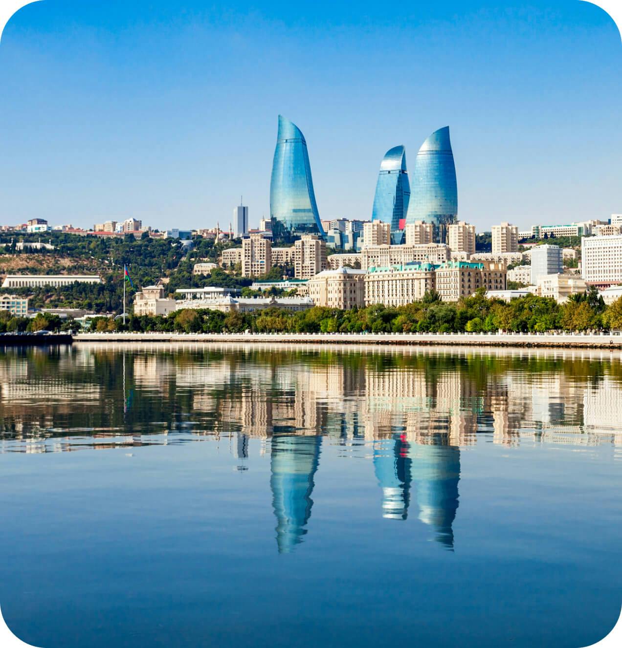 The city of baku is reflected in the water.