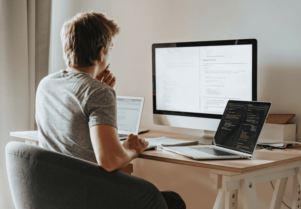 A man ponders his code in a beige room