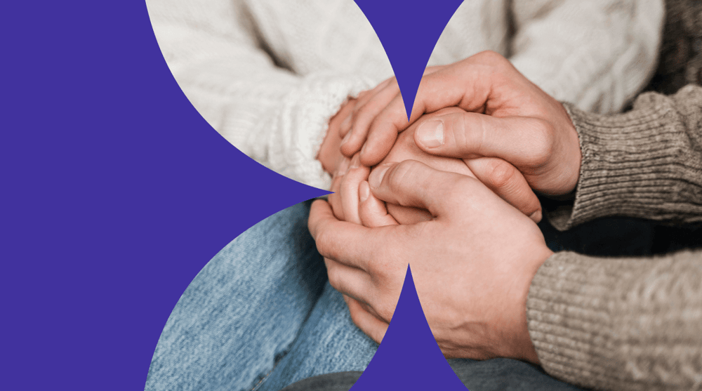 People holding hands to support someone grieving during bereavement or loss.