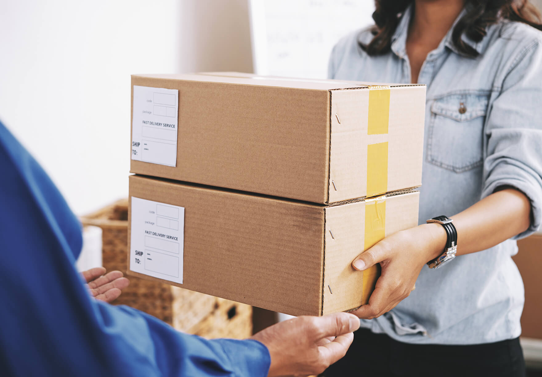 A person delivering boxes to someone with outstretched arms