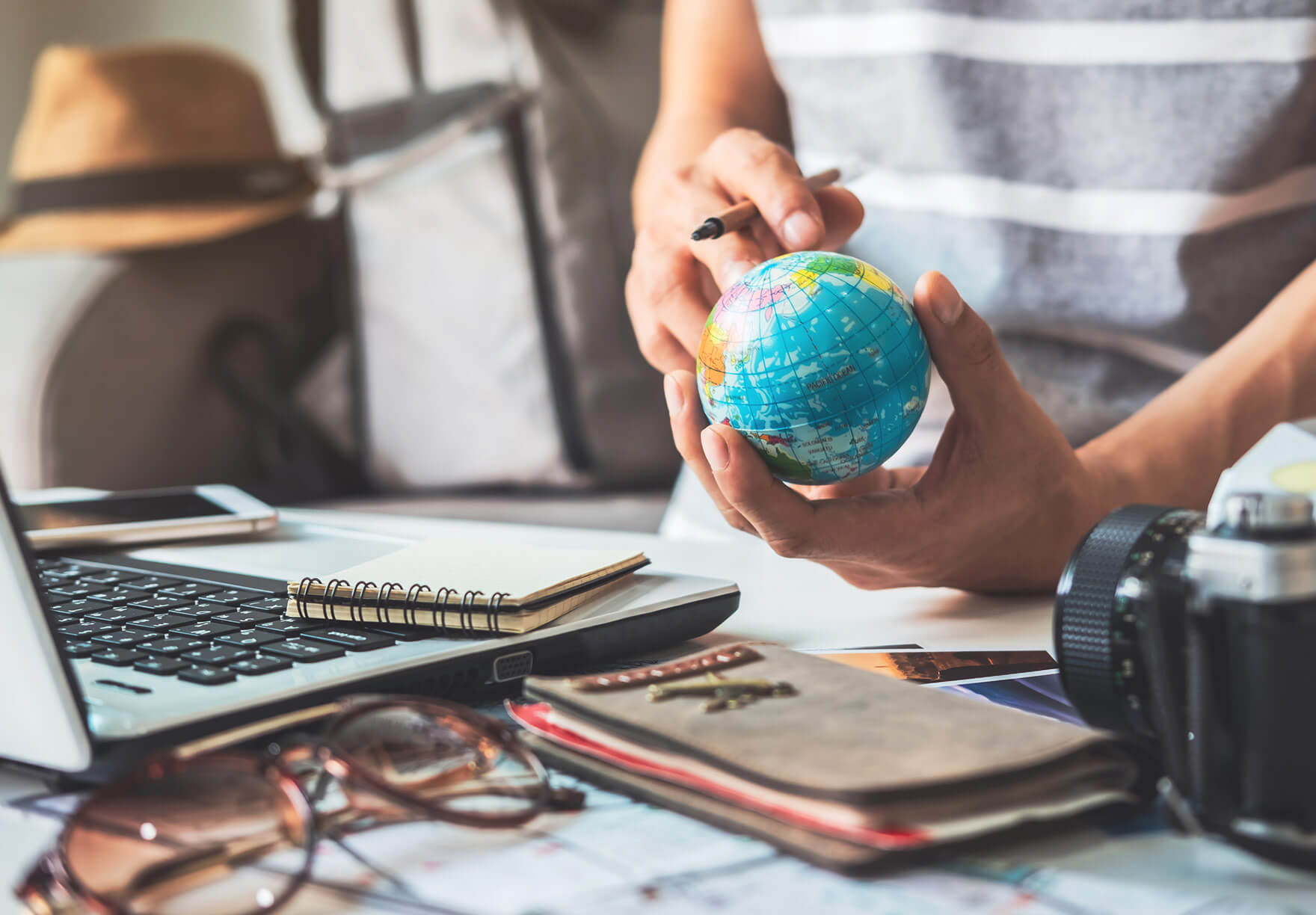 A person holding a globe at a desk