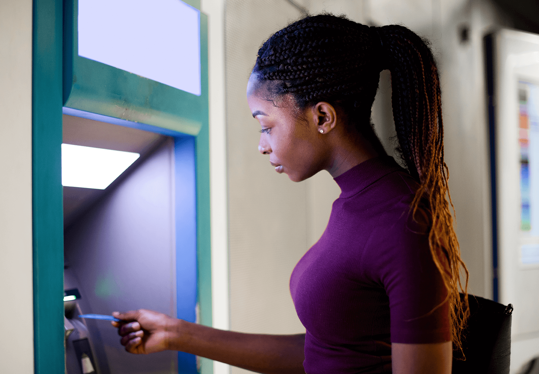 A woman approaching an ATM with her bank card