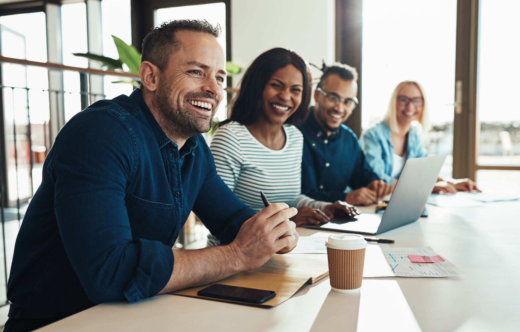 Smiling team members speaking with an international colleague over a video meeting