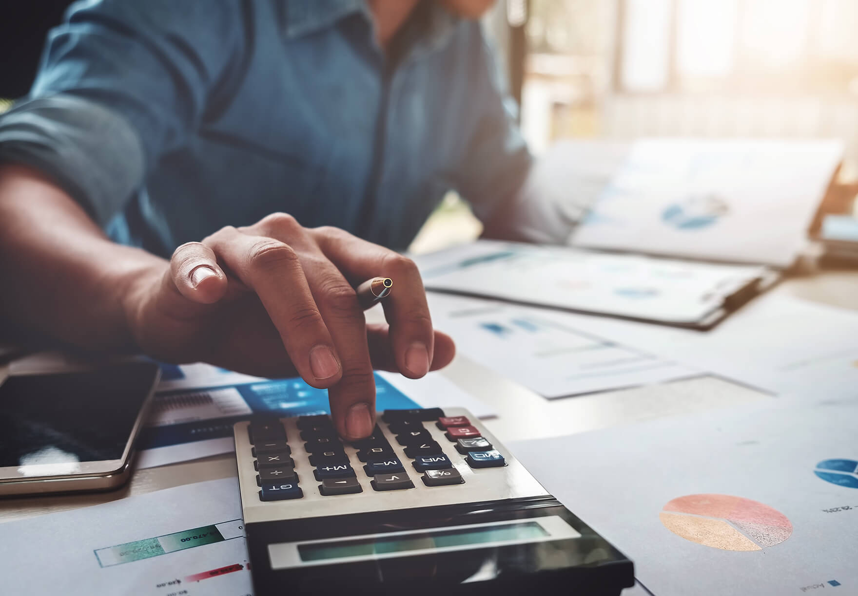 A person types on a calculator to calculate fees